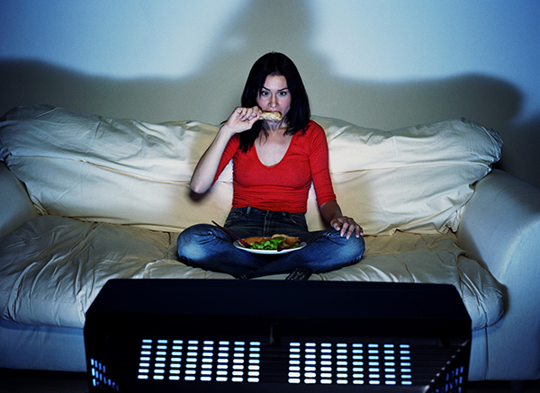Young woman eating and watching television