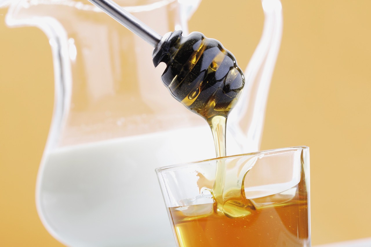 Honey being put in milk --- Image by © Creativ Studio Heinemann/Westend61/Corbis