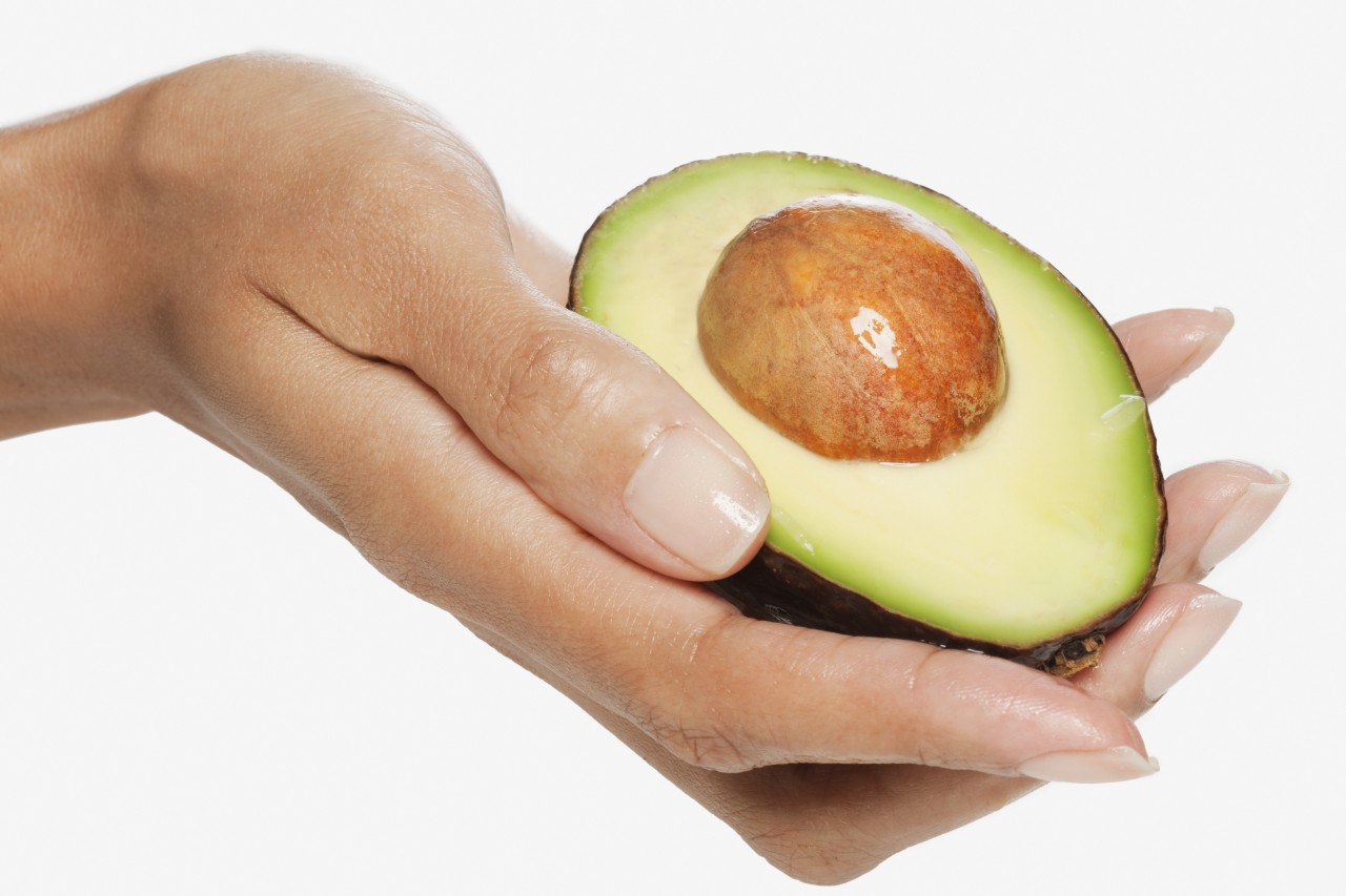 Woman holding sliced avocado --- Image by © Wendy Hope /Corbis