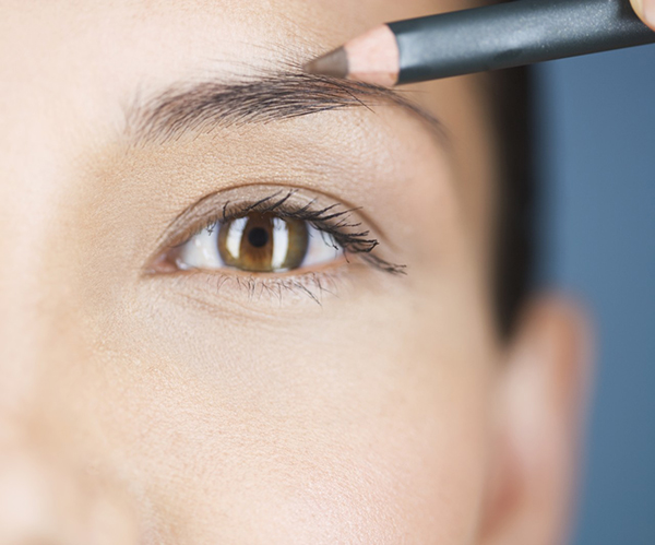 A young woman using an eyebrow pencil --- Image by © I Love Images/Corbis