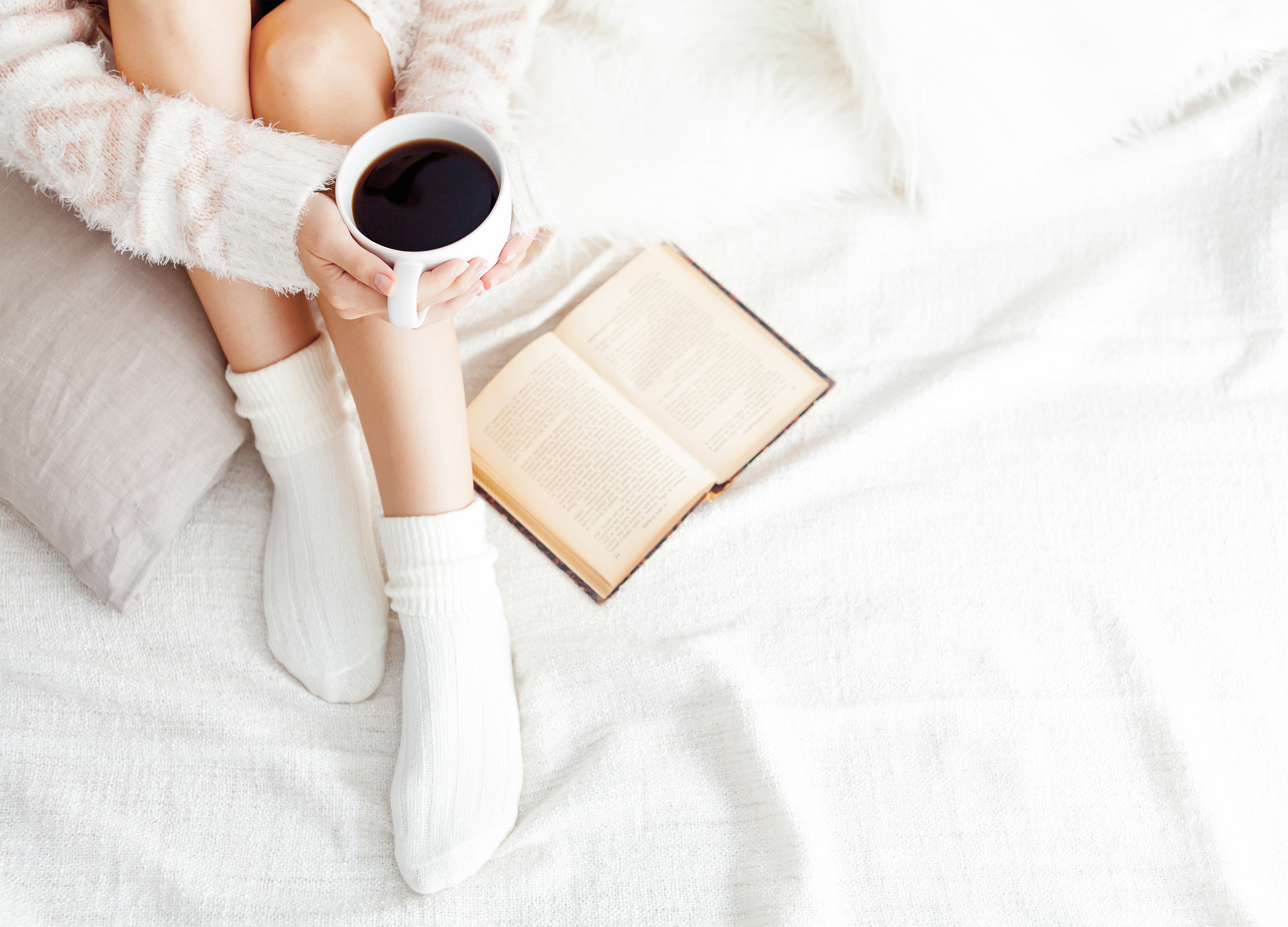 Soft photo of woman on the bed with old book and cup of coffee, top view point